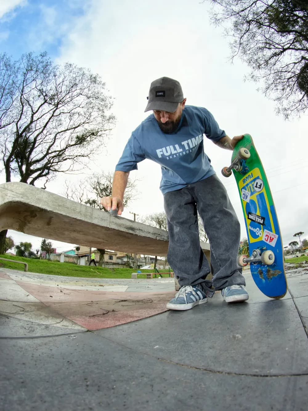Anderson Camargo com o skate na mão, na borda da praça